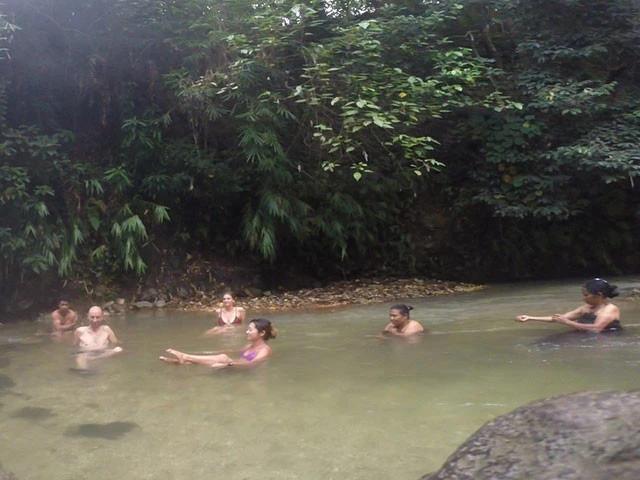 旅友や現地の人々と天然温泉を楽しむ