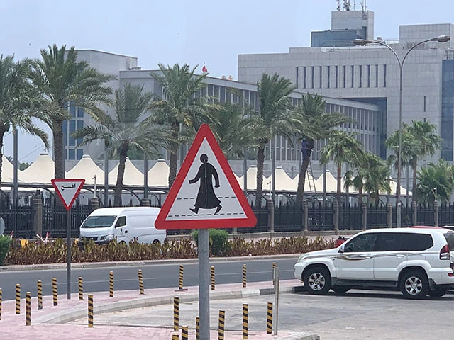 カンドゥーラ姿の道路標識。左奥のアラビア語の標識は「Give way」って意味