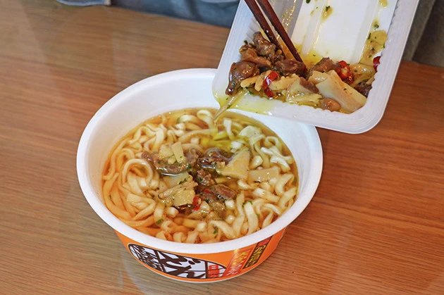 （３）ぶっかけ！　どん兵衛が出来上がったら温めたアヒージョをすべてどん兵衛の上から豪快にぶっかけ、かき揚げをのせたら完成。少しずつ混ぜながら、味の変化を楽しみつつ食べると激ウマ！