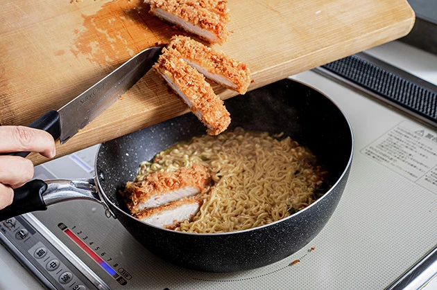 （３）とんかつ！　一口サイズにカットしたとんかつもフライパンに投入し、豚骨スープを吸収させるようにしながら焼き続ける。使用するとんかつはスーパーの惣菜でも冷凍食品でも問題ない