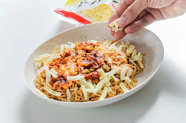 (3)チーズ! 移植したソースの周辺はペヤングの麺がむき出しになっているはず。とろけるチーズを手に取り、麺を覆い隠すようにパラパラと振りかけよう。量はお好みで増減させてOK