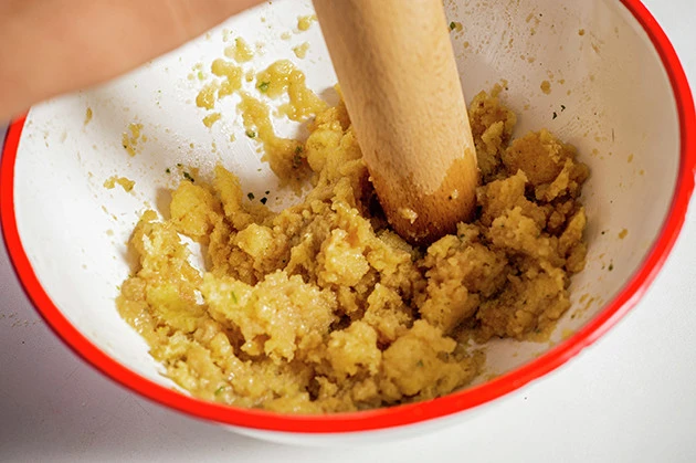 (1)潰す! キャベツ太郎をボウルに移し、水を少量ずつ垂らし入れながらキャベツ太郎全体を潰す。スナックが砕けてペースト状になってきたら、チーズと片栗粉を入れて混ぜ続けよう