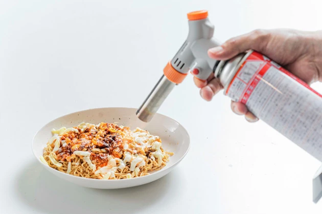 (4)バーナー! ガスバーナーでとろけるチーズをあぶって溶かし、ソースと一体化させたら完成。全体をよくかき混ぜて食べよう。家にガスバーナーがなければオーブントースターでも代用可能だ