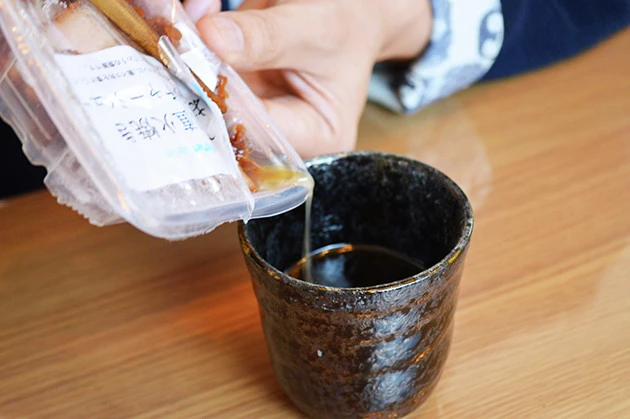 (2)タレ! 付属のタレを容器に入れたら湯切り湯を直接注いで2倍に薄める。さらにチャーシューをレンチンして出た肉汁も注いだらつけ汁の完成。お好みでチューブニンニクを入れても◎