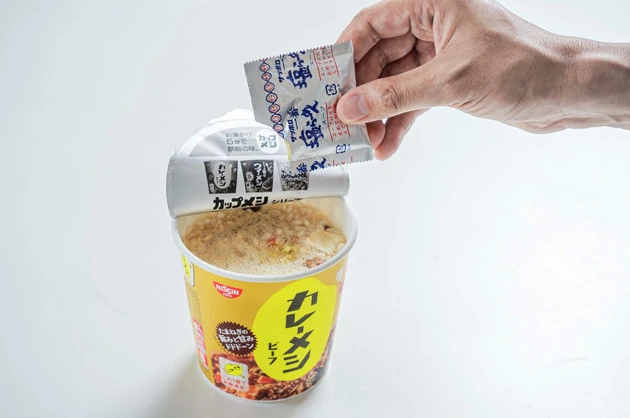 (2)スープ! 続いてカレーメシに熱湯を注ぐが、目安の線よりも1~1.5cmほど上まで注ぐのがポイント。サッポロ一番 塩らーめんのスープも半量ほど入れ、しっかりと全体をかき混ぜよう