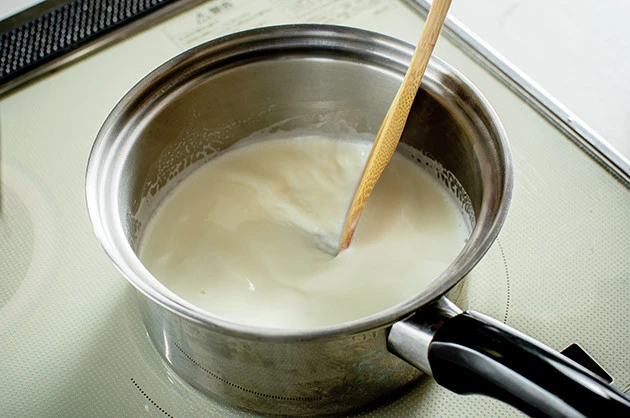 （３）牛乳！　同時に鍋で牛乳も沸騰させておこう。牛乳は非常に焦げつきやすいので要注意。弱火～中火でじっくりと温めながら、おたまや木べらなどを使って常にかき混ぜておこう