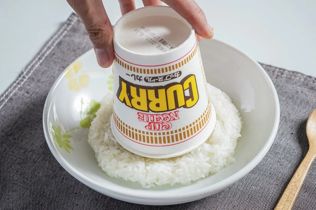 (4)盛りつけ! 盛りつけの際には空き容器にカレーヌードルをいったん戻し、皿に盛りつけたライスの上にひっくり返すとオシャレに仕上げられる。カレーの新境地を堪能せよ!