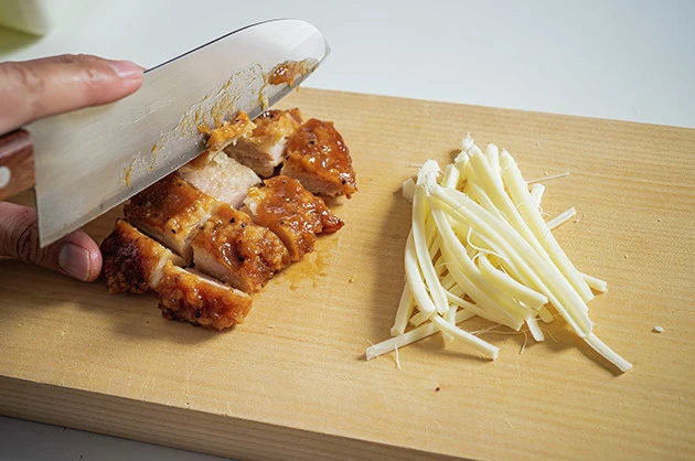 (1)下準備 Lチキのガーリックソース味をひと口大にカットし、さけるチーズを細かく裂く。Lチキはほかのコンビニチキンでも代用可能。カロリーを気にするならサラダチキンでもOK