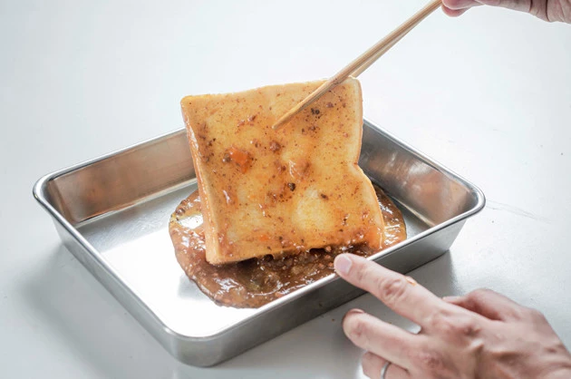 (2)吸収! 食パンを投入し、バットに広げた炒め物のもとをスポンジに吸収させるような感覚で限界まで食パンに吸収させる。箸やトングでひっくり返し、両面ともしっかり吸わせよう