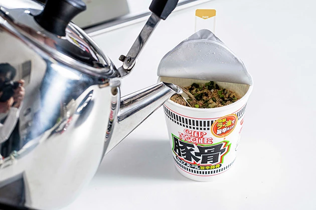 （１）注ぐ！　カップヌードル旨辛豚骨に熱湯を注いで３分待つ。お湯は麺がギリギリ浸るくらいまで減らしてもよい。すぐにウマそうなニオイが漂ってくるが、食べるのはグッと我慢しよう