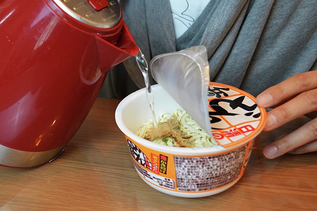 （２）注ぐ！　「砂肝ときのこのアヒージョ風」を温めている間に、どん兵衛を開封して熱湯を注ぐ。どん兵衛が出来上がったときにはアヒージョも温まっているように準備しよう