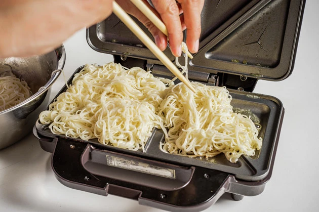 (2)焼く! ゆで上げたそうめんの水を切り、全体にバターを絡めておく。続いてホットサンドメーカーにもたっぷりとバターを塗り、そうめんをのせてフタを閉め、強引に焼き上げよう