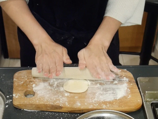 １０．調理台に打ち粉をして生地を綿棒で伸ばし円形の皮を作っていく。（綿棒がなければワインボトルやラップの芯などで代用可）