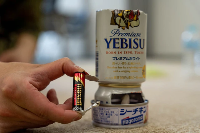 ④ガム電池ライターで着火! 火は40分ほど持続するため、空き缶にお米と水を入れて炊飯も可能だ