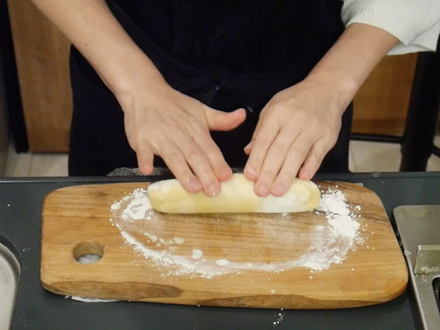 ８．調理台などの上に打ち粉を敷いて、寝かせていた皮を直径５００円硬貨ほどの太さの棒状に伸ばす。