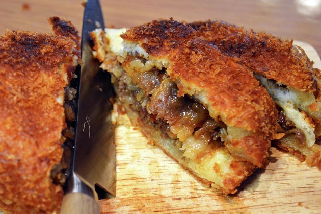 (4)カット! (3)がサクサクに焼き上がったらやけどに気をつけながらまな板の上に移動し、包丁でひと口大にカット。形崩れしないように気をつけながら(1)に添えたら絶品カツカレーの完成!