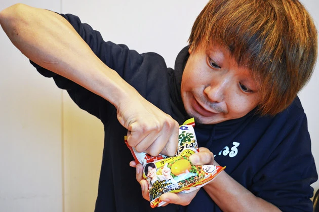 (1)殴る! サッポロ一番の袋を手に取り、袋の上から麺を殴りつけて細かく砕く。あまり強く殴りすぎると袋が破けてしまうので要注意。両手で袋を持ち、麺を割るようにして砕いてもよい