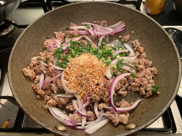 ７．肉に火が通り水分が少しになったら火を止めて、赤玉ねぎ、万能ねぎ、炒り米、ナンプラー、チリパウダー（or唐辛子）、砂糖を入れて全体を和える。