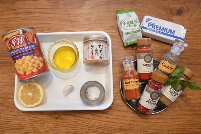 材料。フムス(バット内):ひよこ豆水煮缶、オリーブオイル、練りゴマ、レモン、ニンニク、塩。トッピング:イタリアンパセリ、レッドペッパー、クミンなどのスパイス。付け合わせ:クラッカー