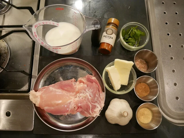 材料：鶏肉、ニンニク、バターの基本材料と牛乳。調味料に塩胡椒、コリアンダーパウダー、フェネグリークパウダー。トッピングにパプリカパウダー、コリアンダー