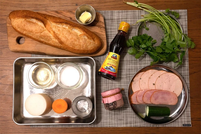 左上から時計まわりに、フランスパン、バター、ヌックマム、パクチー、ハム、チャーシュー、キュウリ、レバーペースト。（トレー内・なます用）酢、砂糖、塩、人参、大根