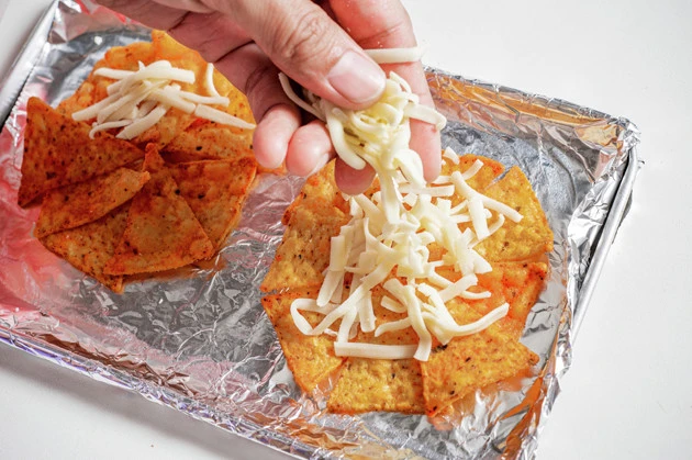 (2)チーズ! 円形に配置したドンタコスの上にチーズを盛りつける。このチーズが溶けることでドンタコスが一体化されるので、隙間なく薄く盛るのがポイント。特に境目には確実に盛ること