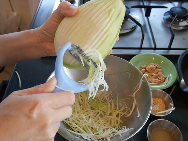 １．洗った青パパイヤの皮をむき、ソムタム用ピーラーなどで細切りにする。（包丁で細切りやささがきにしてもＯＫ）