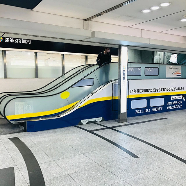 東京駅にて、高低差が少ないエスカレーターの形を生かしたE4系引退の記念ラッピング。運行開始当初の黄色帯のセレクトもうれしい