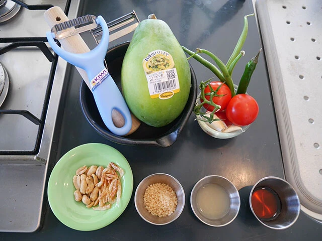 材料：（上段）青パパイヤ、いんげん、ミニトマト、ニンニク、唐辛子、（下段）ピーナッツ、干しエビ、砂糖、ライム汁、ナンプラー