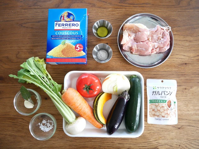 材料。上段左から：クスクス、オリーブオイル、塩、鶏肉。下段左から：ニンニク＆ローリエ、塩＆クミン。バット内：トマト、玉ねぎ、かぶ、にんじん、かぼちゃ、なす、ズッキーニ。ひよこ豆