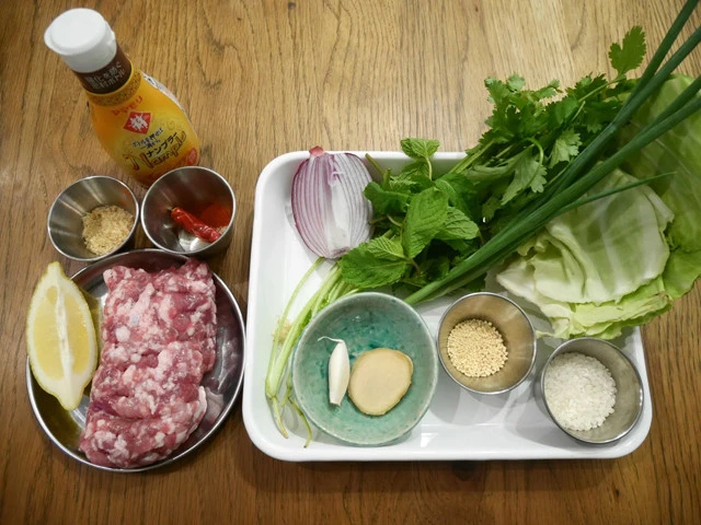 材料:(左から)ナンプラー、砂糖、チリパウダーor唐辛子、レモン、挽肉。(白いバット内、左上から)赤玉ねぎ、パクチー、ミント、万能ねぎ、キャベツ、ニンニク、生姜、鶏ガラスープの素、米