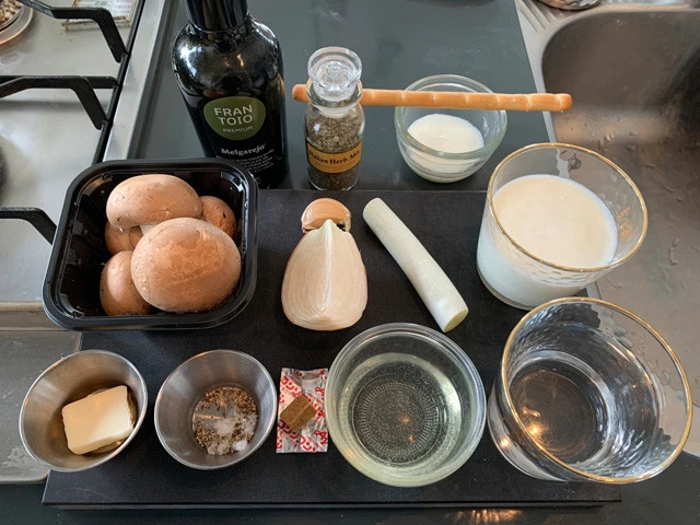 材料:(中段)マッシュルーム、ニンニク、玉ねぎ、長ねぎ、牛乳、(下段)バター、塩胡椒、固形コンソメ、酒、水。(上段)トッピング用のオリーブオイル、パセリ、グリッシーニ、牛乳