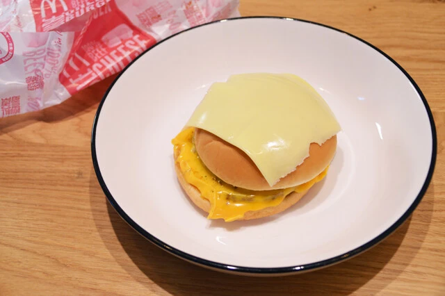 (1)チーズ! マクドナルドのダブルチーズバーガーを食器の中央に置いたら、バンズの上にとろけるスライスチーズを1枚のせる。ダブチが冷めている場合はこの時点で軽くレンチンしよう