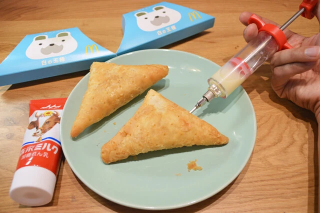 (1)注入! 調理用注射器を用意し、練乳をセットしたら三角チョコパイに注入していく。三角チョコパイのクリームが入っているのは中心部。端の部分にまんべんなく注入していこう