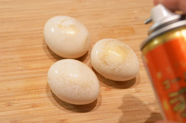 （３）スプレー！　（２）をまな板の上などに並べて金粉スプレーを吹きかける。スプレーを近づけすぎると吹きつけた金粉がすべて飛んでしまうので、距離感に気をつけながら全体を金色に染めよう