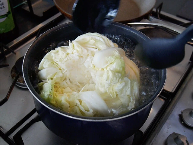 ３．キャベツの芯をくり抜き、塩少々（分量外）を入れた鍋で丸ごと５分ほど茹でたら粗熱を取る。