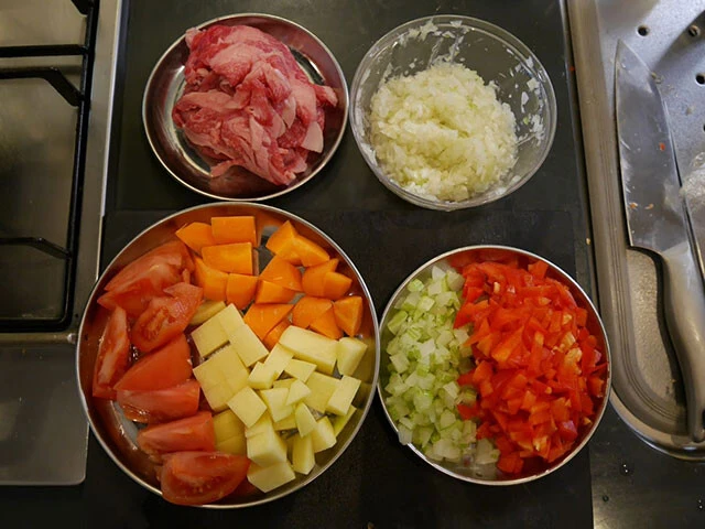 １．赤パプリカ、セロリ、玉ねぎ、ニンニクをみじん切り、トマト、じゃがいも、にんじんは一口サイズに切っておく。肉は塩胡椒（分量外）しておく。