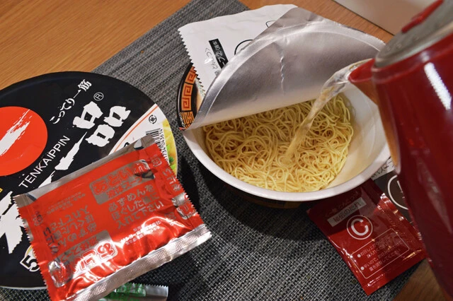 (1)注ぐ! 天下一品のカップ麺と一蘭のカップ麺それぞれを開封し、カップに熱湯を注いで手順どおりに仕上げていく。鍋で最初から混ぜて作ると麺がうまく戻らない可能性があるので注意