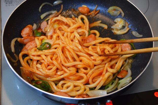 (2)味つけ! うどんをある程度炒めたらケチャップとコンソメを入れて全体をよく混ぜ、味見をしながら味を調える。味つけに自信がない人はもちろん市販のソースを使用しても問題ない