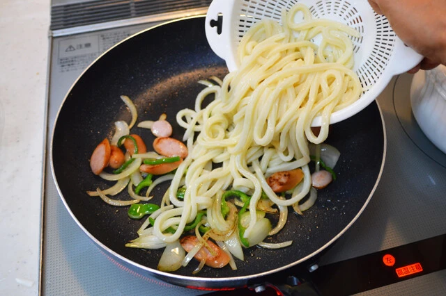(1)炒める! ピーマン、タマネギ、ソーセージなどの具材を切ってフライパンで炒め、火が通ったら丸亀製麺のうどんを入れてさらに炒める。うどんは入れる前に軽く水でほぐすと炒めやすい