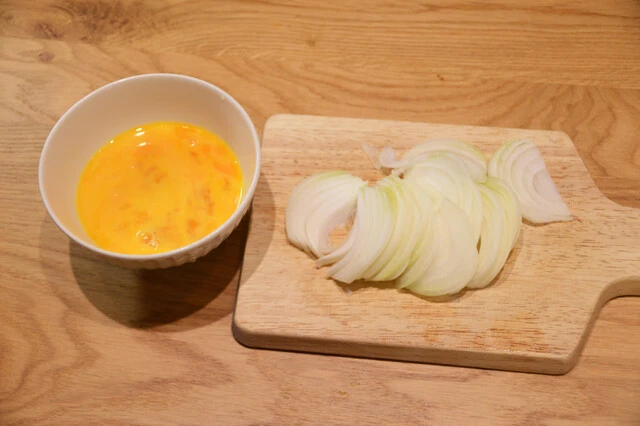(1)下準備! まずは卵とじの下準備から。タマネギを薄くスライスし、卵を割って溶き卵にしよう。今回は卵2個で作っているが、卵感を強めにしたいなら3個、4個と増やしても問題ない