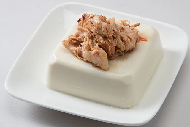 辛味噌チキンの冷ややっこ【ほぐしサラダチキン＋豆腐】①サラダチキンをほぐし、とんこつ辛味噌を加えてあえる②豆腐にのせて、仕上げにお好みでゴマを散らしたら完成