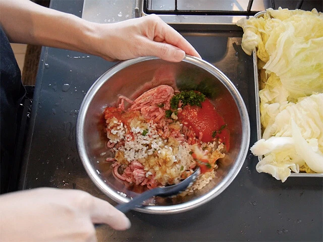 ２．玉ねぎ、ニンニクのみじん切りをフライパンで炒め粗熱を取ったらボウルに入れ、挽肉、米、トマトピューレ、刻んだパセリ、塩胡椒を混ぜてタネの出来上がり。（炒めるのを省略し、全てをボウルで混ぜるだけでもＯＫ）