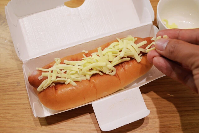 （２）のせる！　（１）をパンに戻したらチーズをたっぷりとのせ、トースターで軽く焼いてチーズを溶かそう。モスのホットドッグはパンが柔らかめ。軽く焼くことで程よい硬さに仕上がるのだ