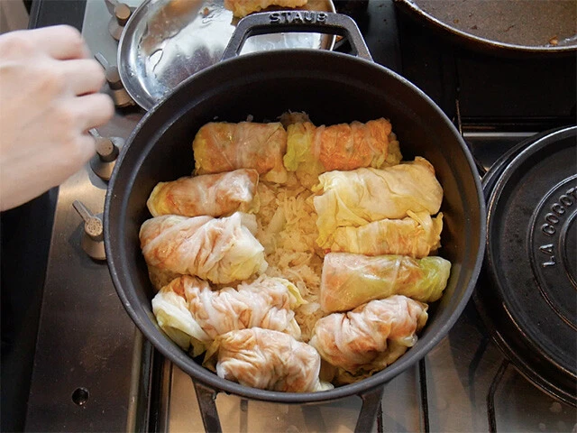 ６．鍋底に余ったキャベツや芯を千切りにして敷き（あればザワークラウトも）、その上に包んだ５を並べる。