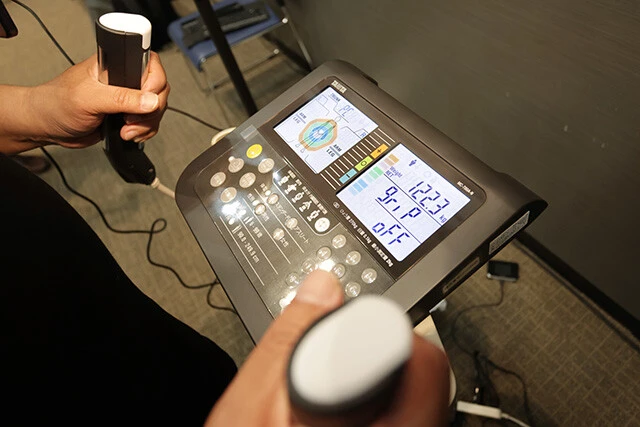 タブレットの操作を除けば、測定方法は体組成計とまったく変わらない。はだしで体組成計に乗り両手でグリップを握って計測
