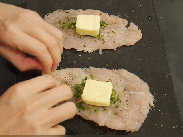 ２．肉全体に塩胡椒をし、にんにく、パセリ、バターを乗せたら、はみ出さないように巻いて包む。