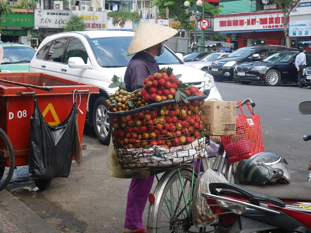 ベトナム伝統の「ノンラー」をかぶった行商人。カゴの中身は「ランブータン」「リュウガン」というライチに似た果物