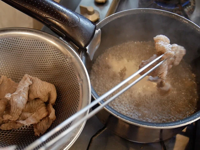 ２．牛肉をサッと茹でザルにあげ、鍋のアクは取り除く