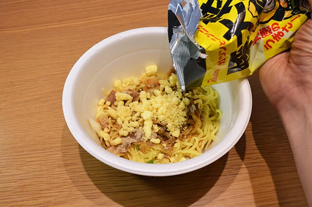 (2)まぶす! 「豚大将」を開封する前に握りつぶして粉々にし、(1)にたっぷりと振りかけてよくかき混ぜる。当然だが量が多いほどニンニク風味が濃くなる。デートの予定がある人は要注意だ